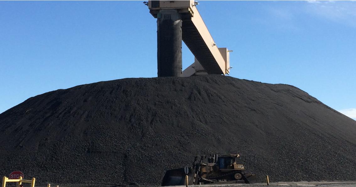 a large pile of black dirt with a crane on top