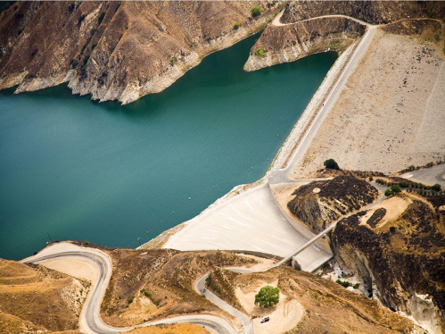 a road next to a body of water with a dam in it