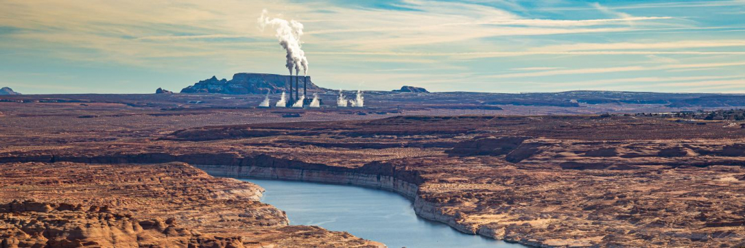 a landscape with a river and smoke stacks