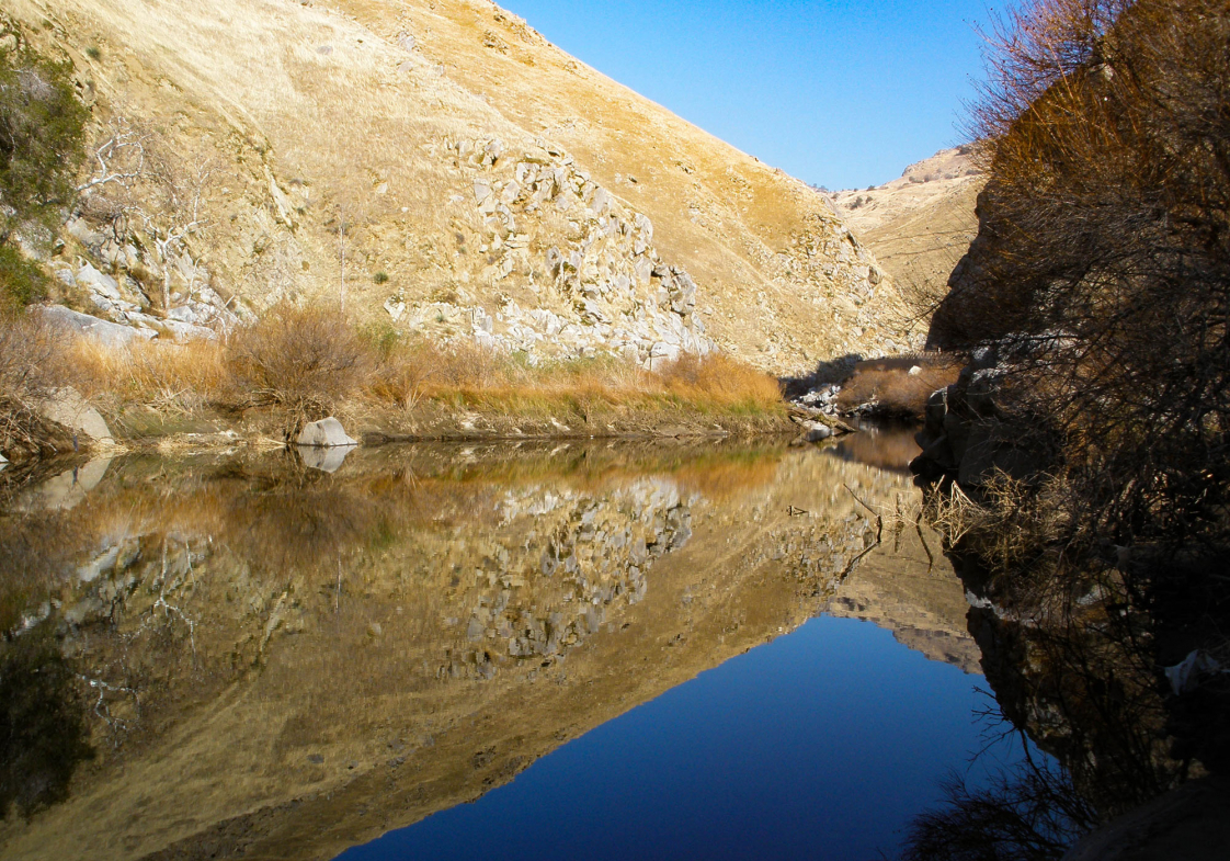 a body of water with a rocky hill and trees