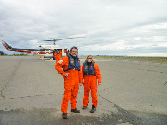 Two people standing in front of a helicopter